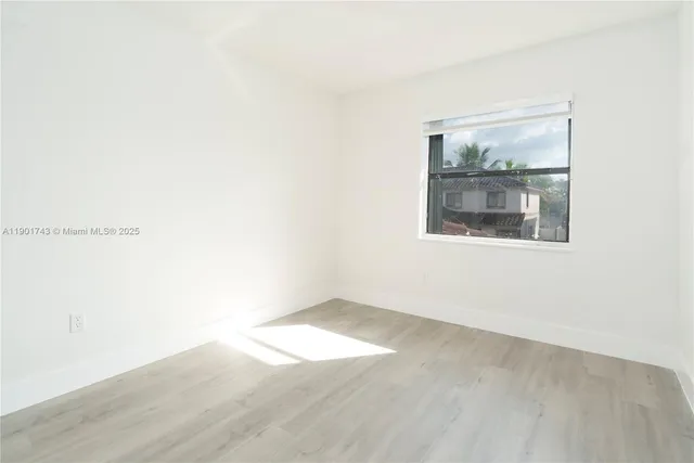 an empty room with wooden floor and a window