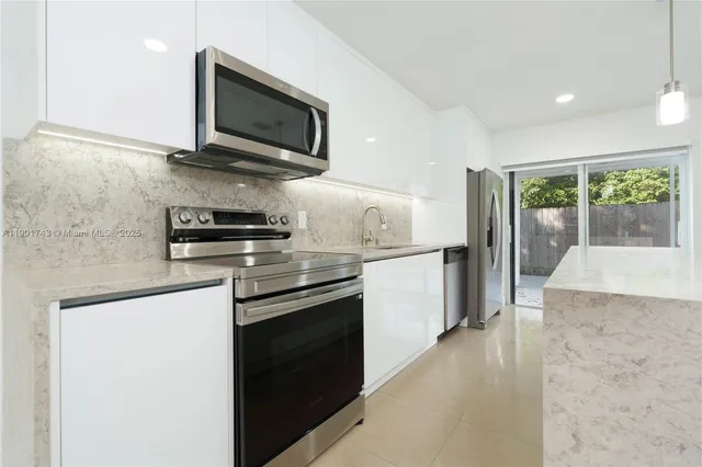a kitchen with stainless steel appliances granite countertop a stove a sink and a microwave