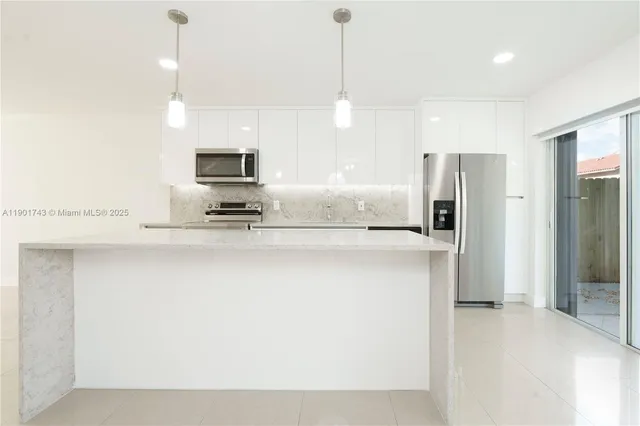 a kitchen with kitchen island a refrigerator and a sink