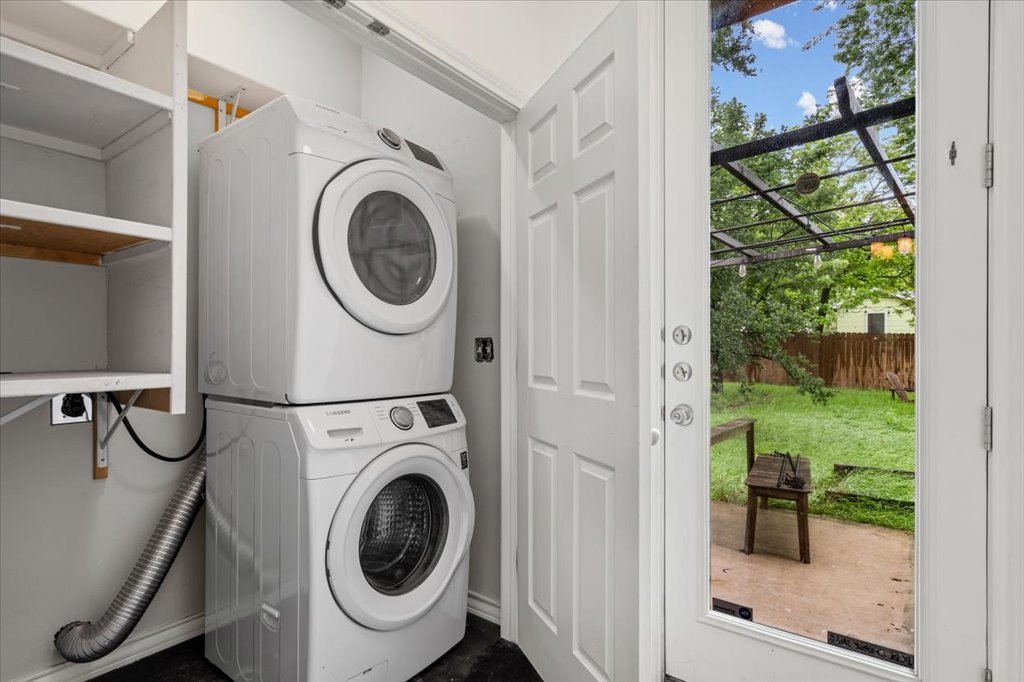 2947 Moss Street Austin, TX 78722 - Photo 15 of 20 Laundry area featuring a stacked washer and dryer, built-in shelving, and direct exterior access to a concrete patio and fenced yard