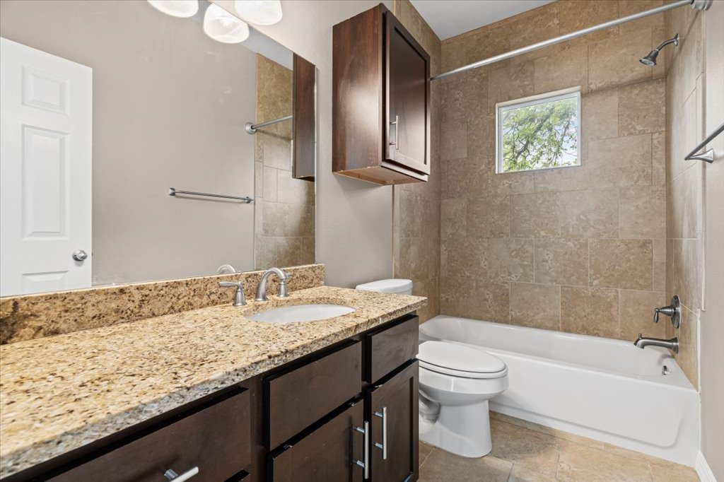 2947 Moss Street Austin, TX 78722 - Photo 16 of 20 Bathroom featuring a granite-top vanity with undermount sink, dark wood cabinetry, and a full-width mirror