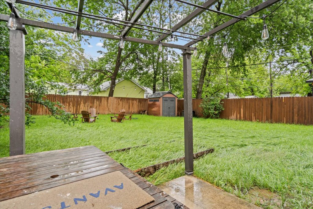 2947 Moss Street Austin, TX 78722 - Photo 19 of 20 Expansive backyard featuring a metal pergola with string lighting, a wooden privacy fence, and a storage shed