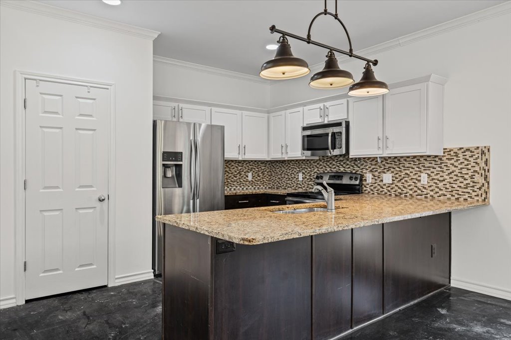 2947 Moss Street Austin, TX 78722 - Photo 6 of 20 Kitchen featuring granite countertops, white cabinetry, a mosaic tile backsplash, stainless steel appliances, and a three-light pendant fixture