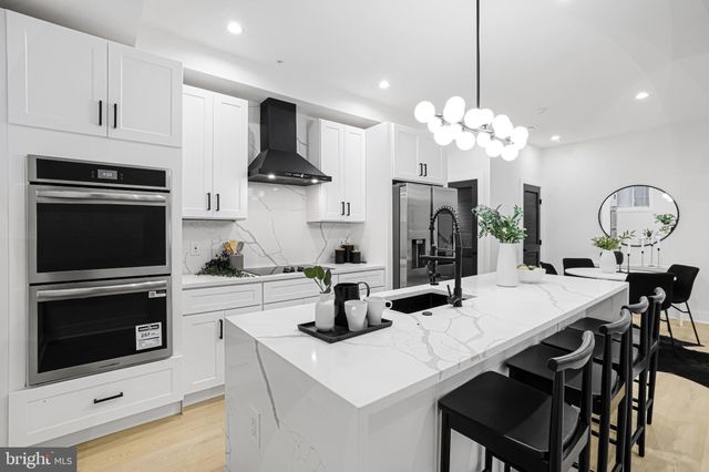 a kitchen with stainless steel appliances a table chairs and a refrigerator