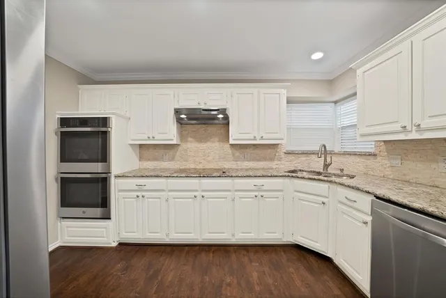 a kitchen with granite countertop white cabinets and a sink