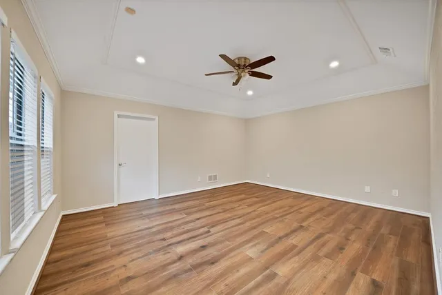 a view of empty room with wooden floor and fan