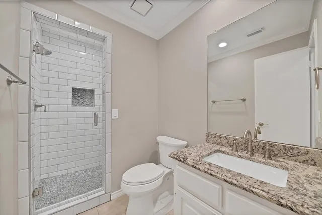 a bathroom with a granite countertop sink a toilet a mirror and shower