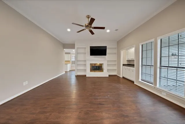 a view of a livingroom with a flat screen tv wooden floor and a ceiling fan