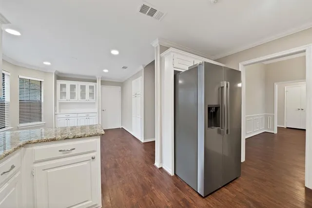 a view of a hallway with wooden floor and cabinets