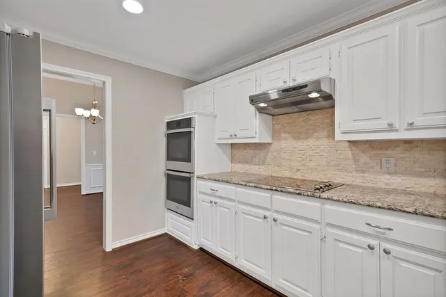 a kitchen with stainless steel appliances granite countertop a refrigerator and white cabinets