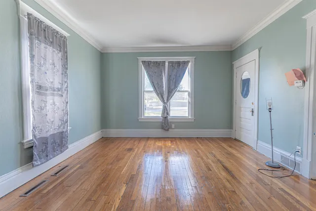 a view of an empty room with wooden floor and a window