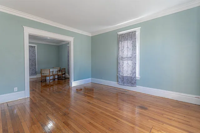 a view of empty room with wooden floor and dining table