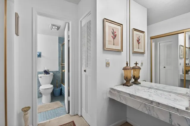 a bathroom with a granite countertop sink and a toilet