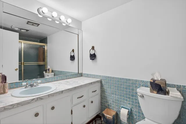 a bathroom with a granite countertop sink mirror and toilet
