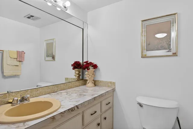 a bathroom with a granite countertop sink a toilet and a mirror