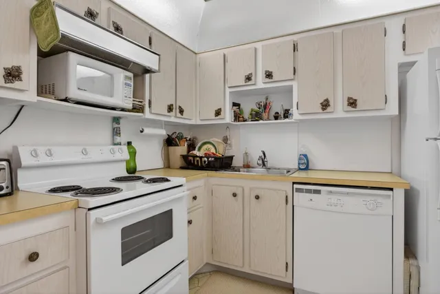 a kitchen with granite countertop white cabinets and white appliances