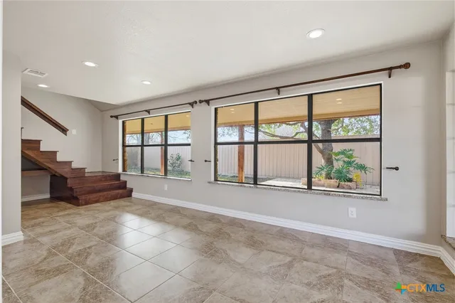 an empty room with furniture and large windows