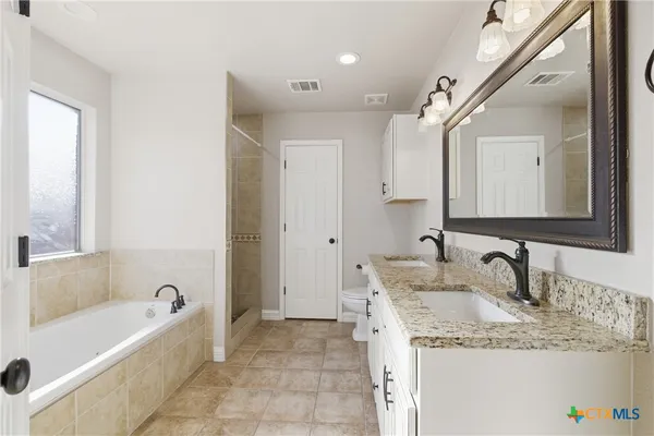 a bathroom with a granite countertop bathtub a sink and a mirror