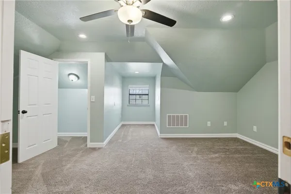 an empty room with chandelier fan and windows