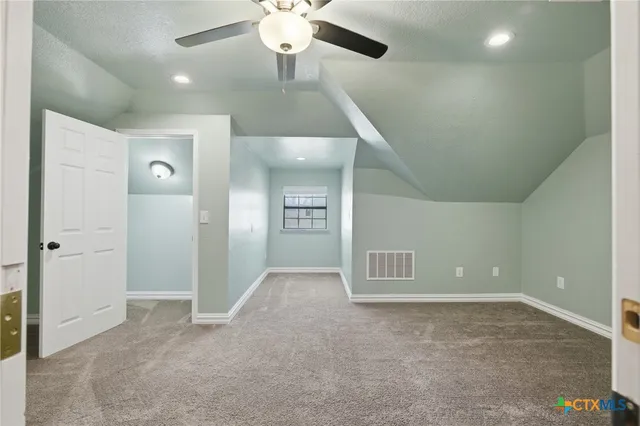 an empty room with chandelier fan and windows
