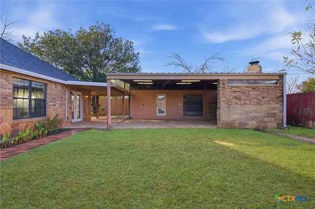 a view of a house with backyard and tree