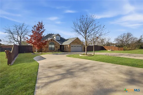 a view of a house with a big yard and large trees