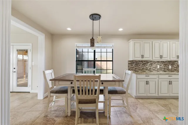 a kitchen with stainless steel appliances granite countertop a dining table chairs and granite counter tops