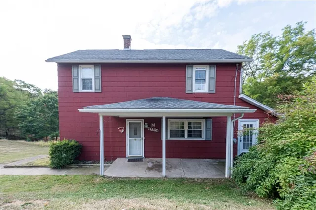 an aerial view of residential house with outdoor space and trees all around
