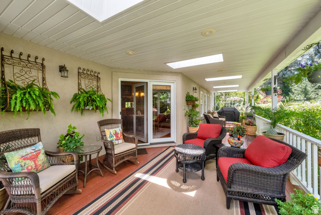 7740 Keswick Road Sandy, UT 84093 - Photo 52 of 74 Spacious covered porch with multiple skylights and recessed lighting, featuring wood-finish flooring, a white railing, and exterior wall sconces