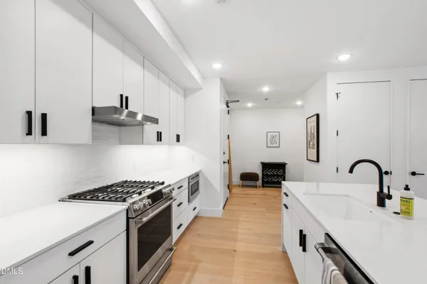 a large kitchen with stainless steel appliances granite countertop a lot of counter space and wooden floors