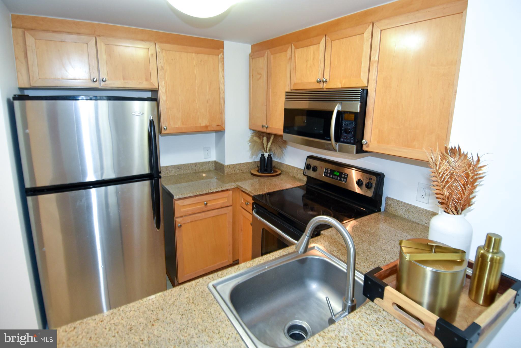 1150 K Street Northwest, Unit 408 Washington, DC 20005 - Photo 14 of 32 a kitchen with stainless steel appliances granite countertop a refrigerator a stove top oven a sink and dishwasher