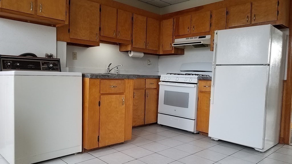 38-40 Pleasant Street Reading, MA 01867 - Photo 9 of 25 a kitchen with stainless steel appliances granite countertop a refrigerator a stove and a sink