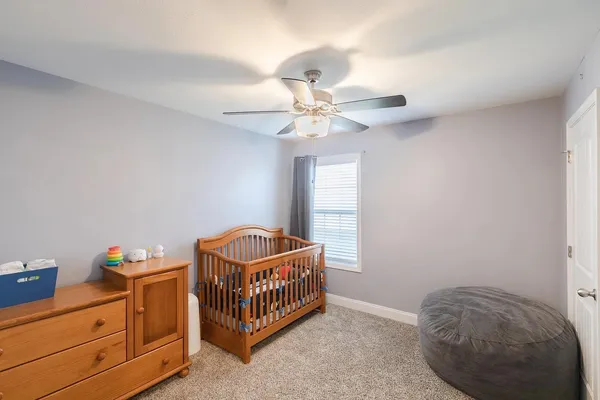 a bedroom with a baby bed a chandelier and dresser