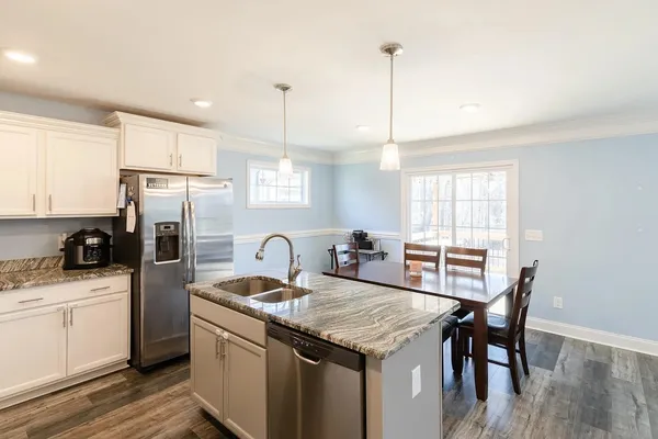 a kitchen with granite countertop a sink a counter space appliances and cabinets
