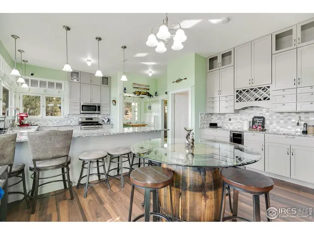 a kitchen with kitchen island granite countertop a table chairs sink and cabinets