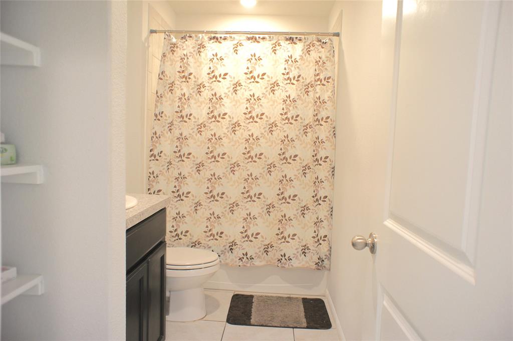 16428 Milwaukee Street Justin, TX 76247 - Photo 5 of 16 a bathroom with a toilet and a shower curtain