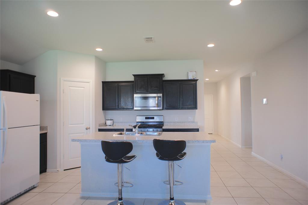 16428 Milwaukee Street Justin, TX 76247 - Photo 8 of 16 a kitchen with stainless steel appliances kitchen island refrigerator sink and cabinets