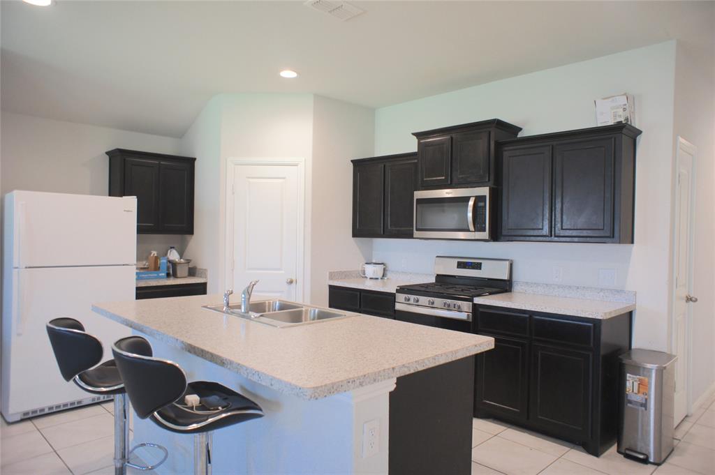 16428 Milwaukee Street Justin, TX 76247 - Photo 9 of 16 a kitchen with a sink and a stove top oven with wooden floor