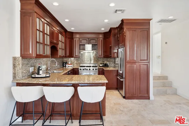 a kitchen with stainless steel appliances granite countertop a refrigerator a sink a stove a dining table and chairs