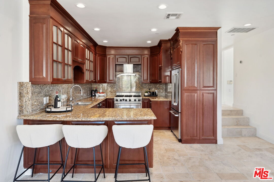 8031 Floral Avenue Los Angeles, CA 90046 - Photo 11 of 34 a kitchen with stainless steel appliances granite countertop a refrigerator a sink a stove a dining table and chairs