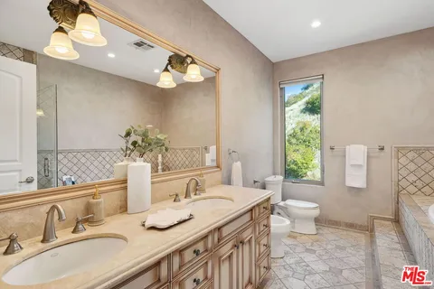 a bathroom with a granite countertop sink a toilet and a mirror