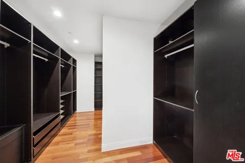 a view of walk in closet with clothes and shoes