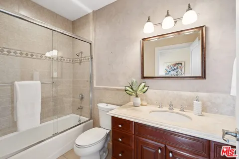 a bathroom with a granite countertop sink toilet a large mirror a shower and bathtub