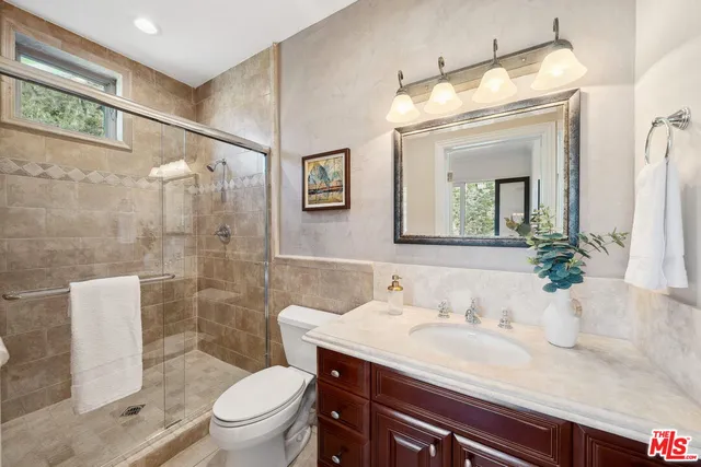 a bathroom with a granite countertop sink toilet a mirror and shower