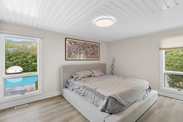 a bedroom with a bed painting on wall and a large window