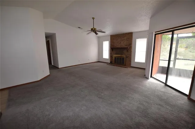 an empty room with windows and fireplace