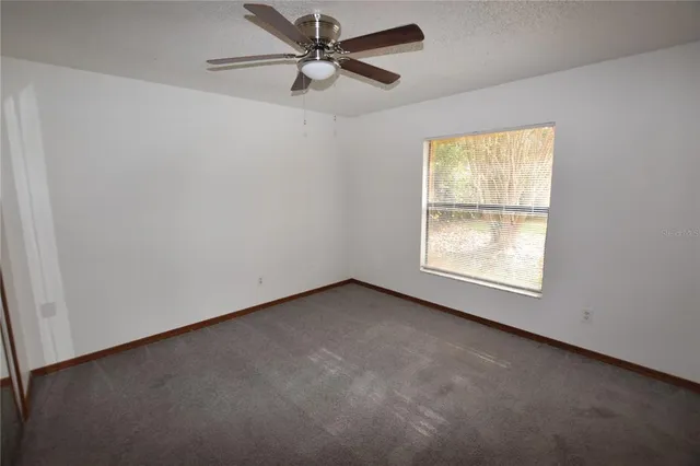 an empty room with a window and a fan