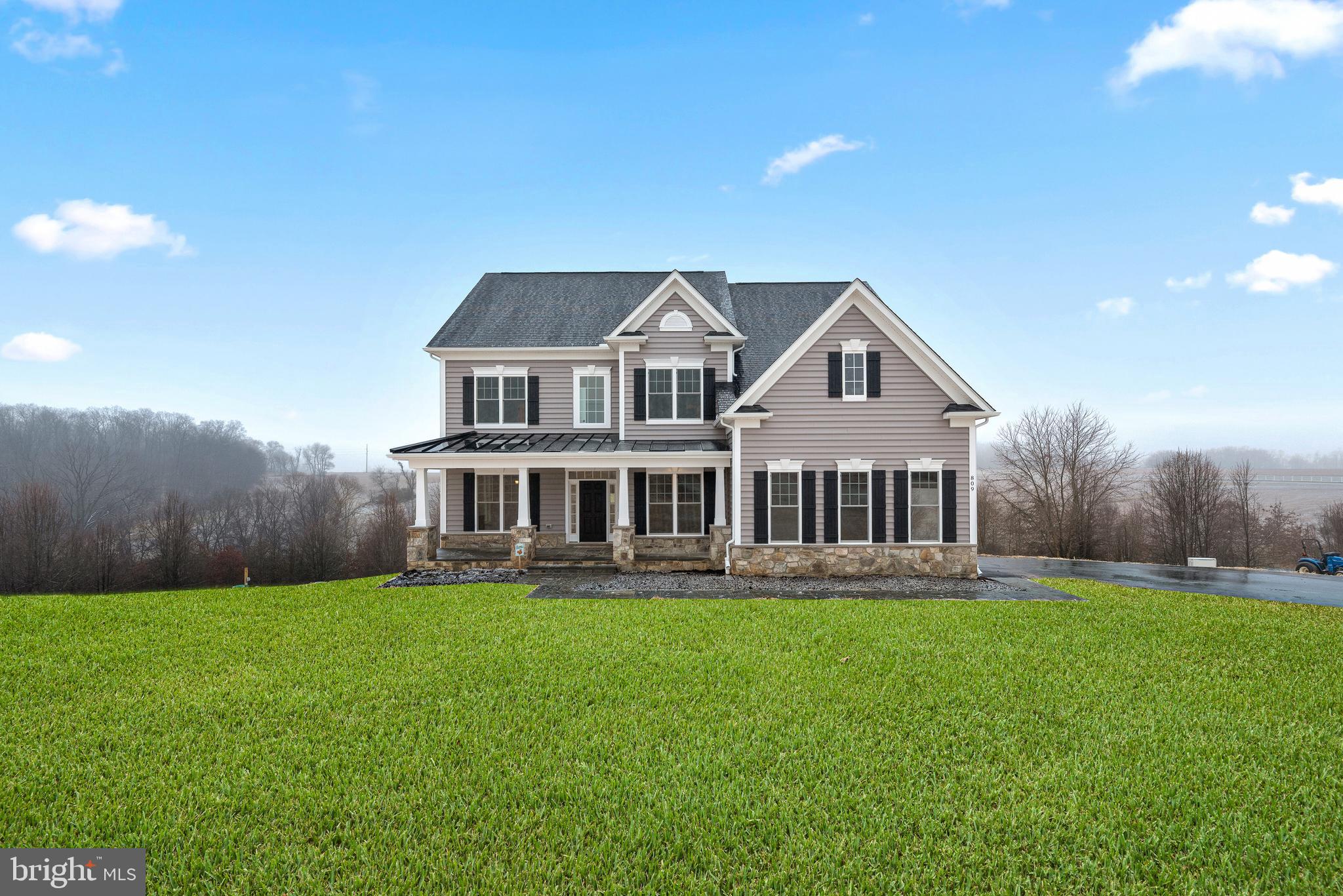 a front view of a house with a garden and trees