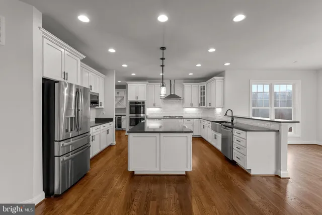 a large kitchen with stainless steel appliances granite countertop a stove and a wooden floors