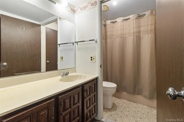 a bathroom with a sink a toilet a mirror and shower curtain